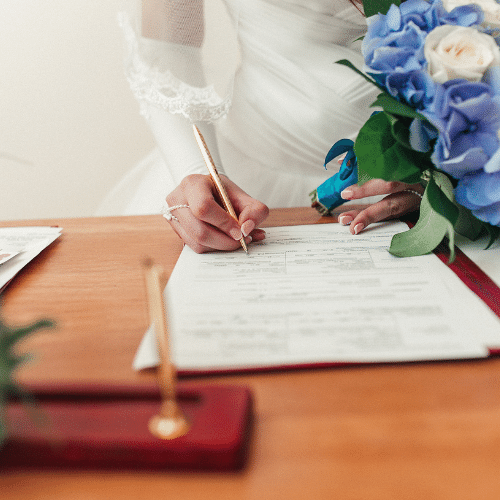 Braut unterschreibt die Eheurkunde nach der Hochzeit.